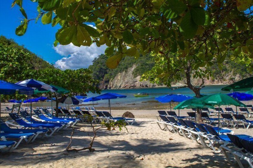 A beach with rows of sun loungers and umbrellas, a clear sky, and a coastline with cliffs. 3