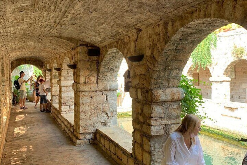 An ancient stone bridge with arches, a paved walkway, and a small body of water. 1