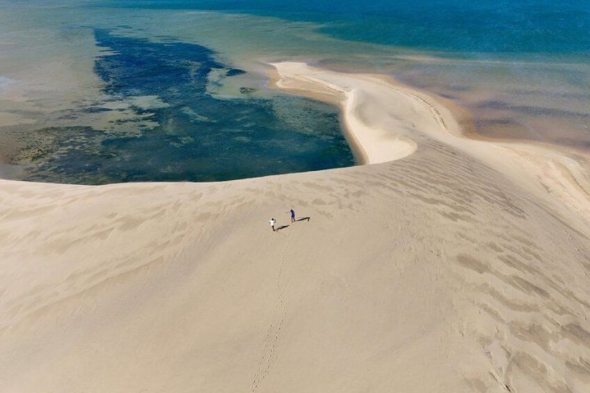 A vast desert landscape with a small group of people walking on a sandy path. 2
