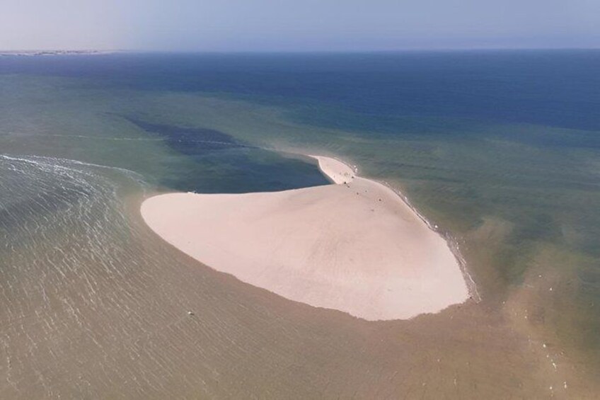 A sandy beach with clear blue water and a distant shoreline. 4
