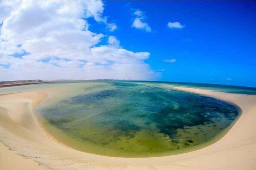 A beach with clear turquoise water, a sandy shore, and a clear sky. 3
