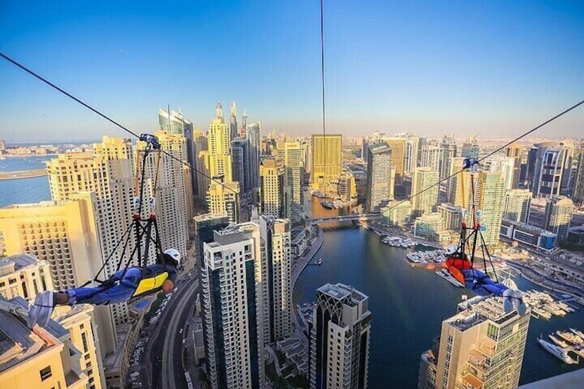 A cityscape with high-rise buildings, a body of water, and a cableway system. 5