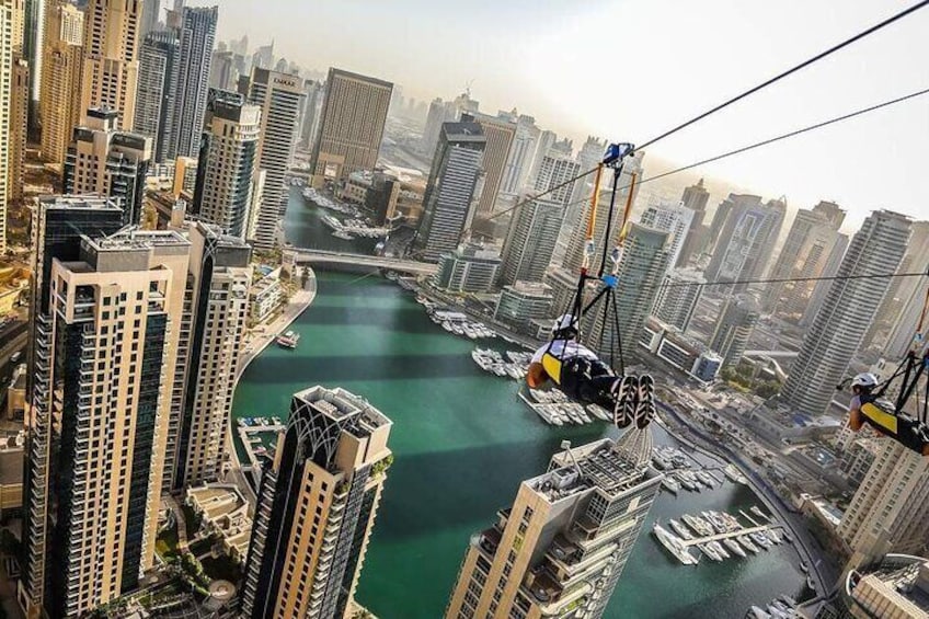 A cable car system in a city with tall buildings and a body of water. 1