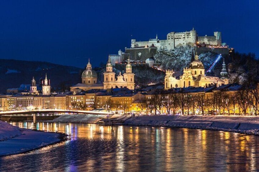 Un paisaje urbano nocturno con edificios iluminados y un castillo en una colina. 3