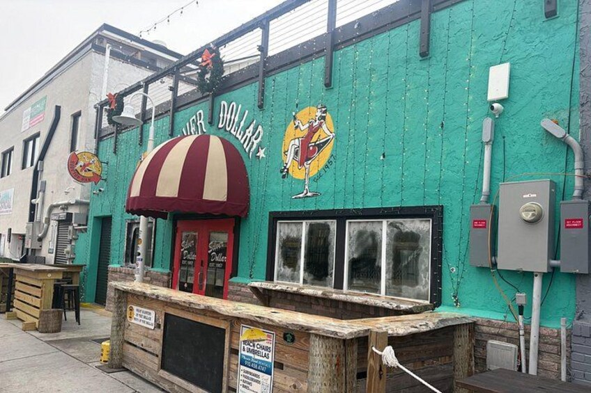 A building with a green exterior, a red and white striped awning, and a sign that reads 'HIGH DOLLAR.' 3