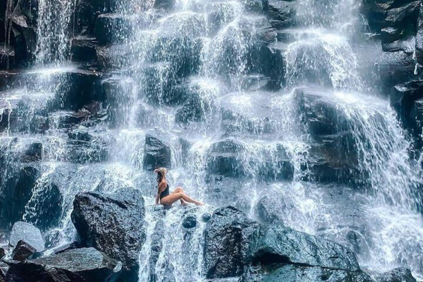 A person sitting on rocks by a cascading waterfall. 4