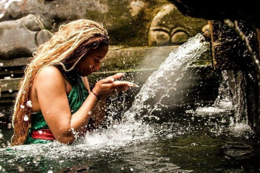 A person in a green dress near a water fountain with water splashing around. 1