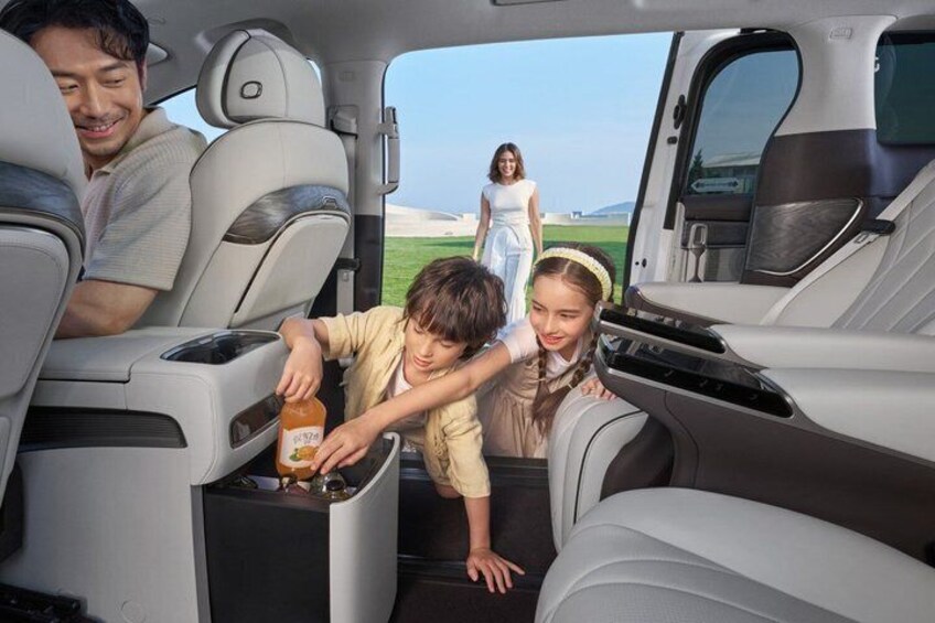 A vehicle interior with passengers interacting near the rear seat. 3