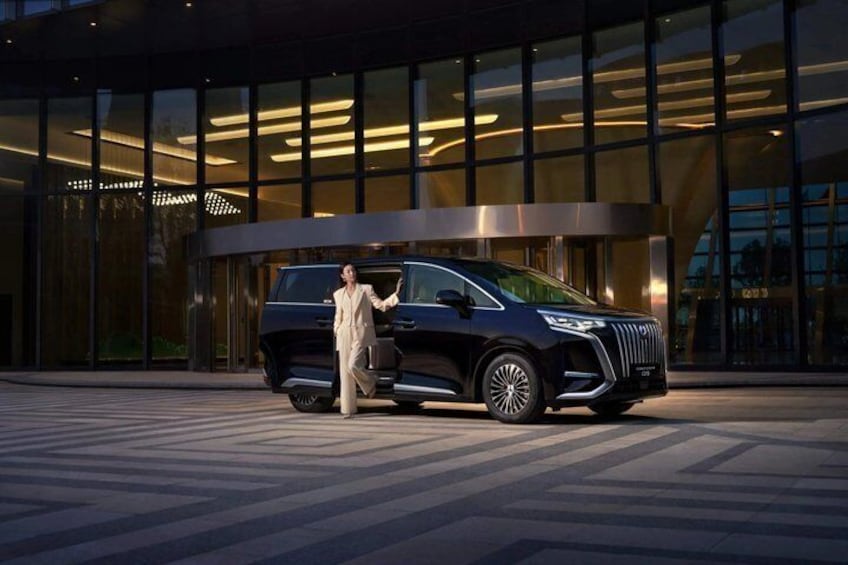A dark-colored SUV parked in front of a modern building with large windows and a curved entrance. 1