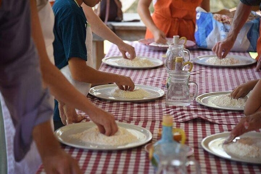People preparing food at a table with checkered tablecloths. 1