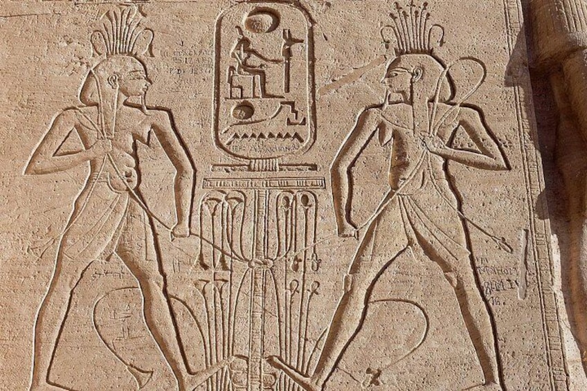 Relieve egipcio antiguo con dos figuras, jeroglíficos y un emblema central. 4