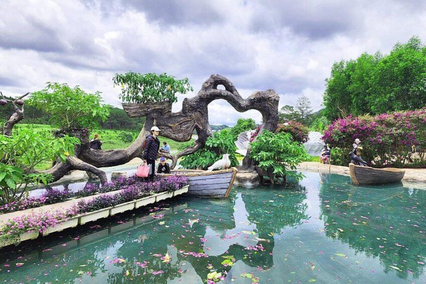 A serene garden with a koi pond, a wooden bridge, and a large tree sculpture. 4