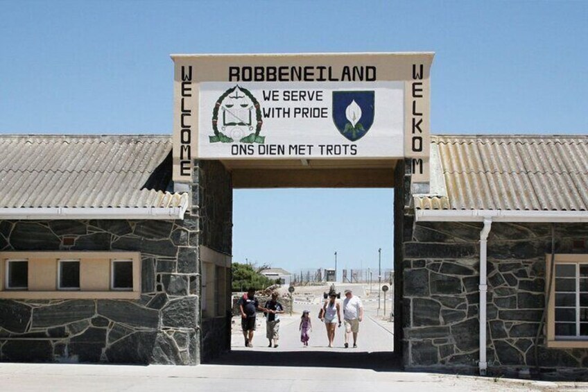 A stone archway with a sign reading "Robben Island" and "Welkom" welcoming visitors. 1
