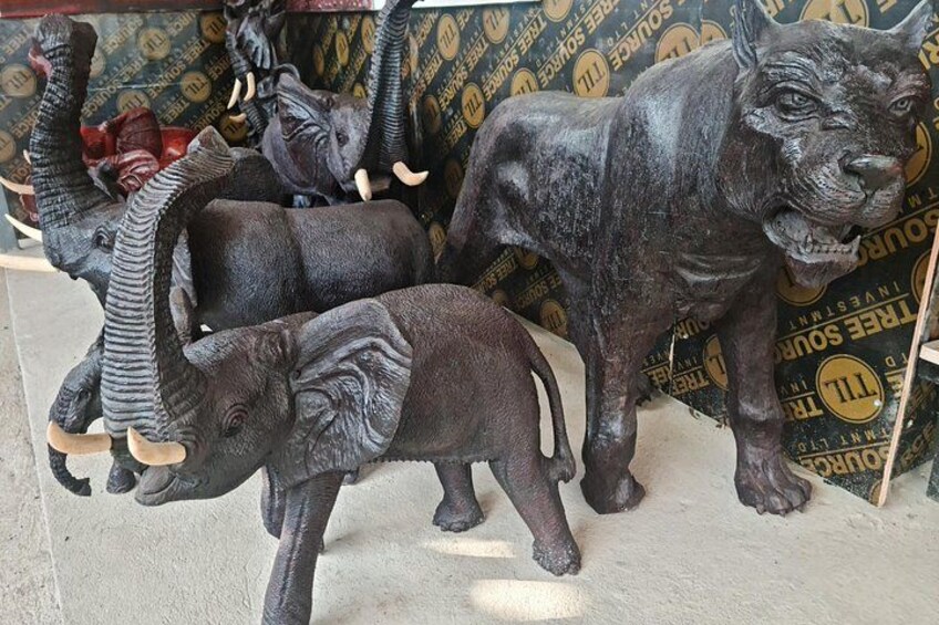 Una colección de esculturas de animales, incluyendo elefantes y un león, exhibida sobre un fondo estampado. 3