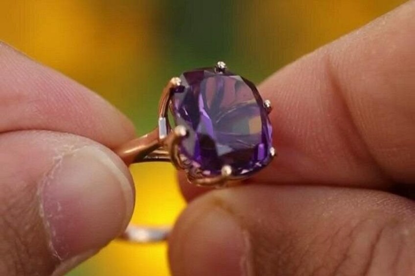 Una mano sosteniendo un anillo con una gema púrpura. 2