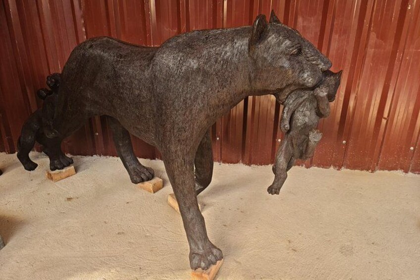 Una escultura de un caballo sobre un piso color beige con un fondo de metal corrugado rojo. 4