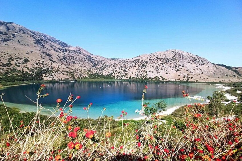 Un lac entouré de montagnes, avec des fleurs rouges au premier plan. 2