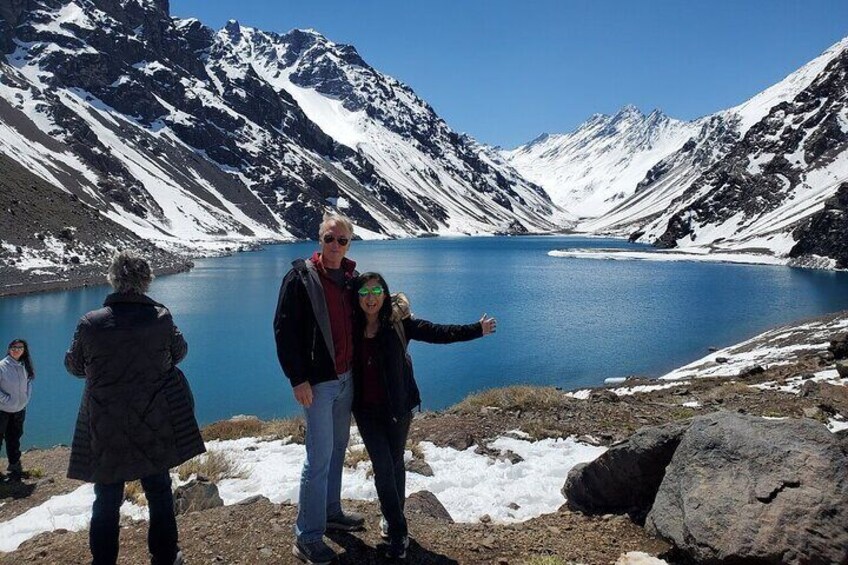 Un grupo de personas de pie junto a un lago rodeado de montañas nevadas. 2
