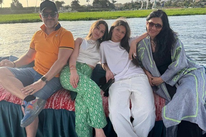 A group of people sitting on a boat by a calm body of water with greenery in the background. 4