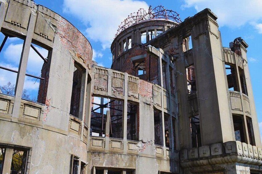 A dilapidated building with exposed brickwork, large windows, and a circular structure with a metal framework on top. 1