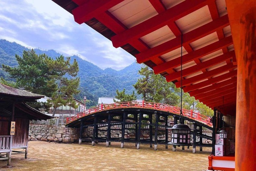 Een traditionele Japanse brug met een rood dak, omgeven door een stenen muur en een houten gebouw. 5