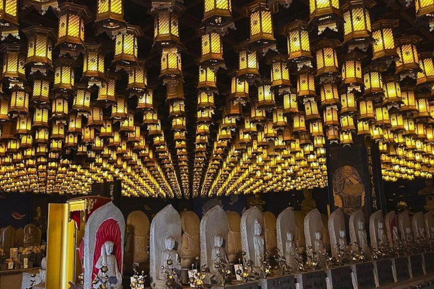 Een tempelinterieur met rijen verlichte lantaarns en beelden. 2