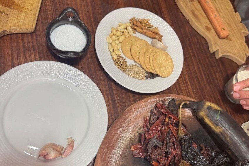 A wooden table with various food items, including a plate with sliced bread, a bowl of chickpeas, and a bowl of dried chilies. 5