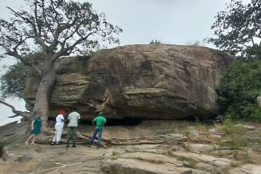 A large rock formation with people standing around it. 3