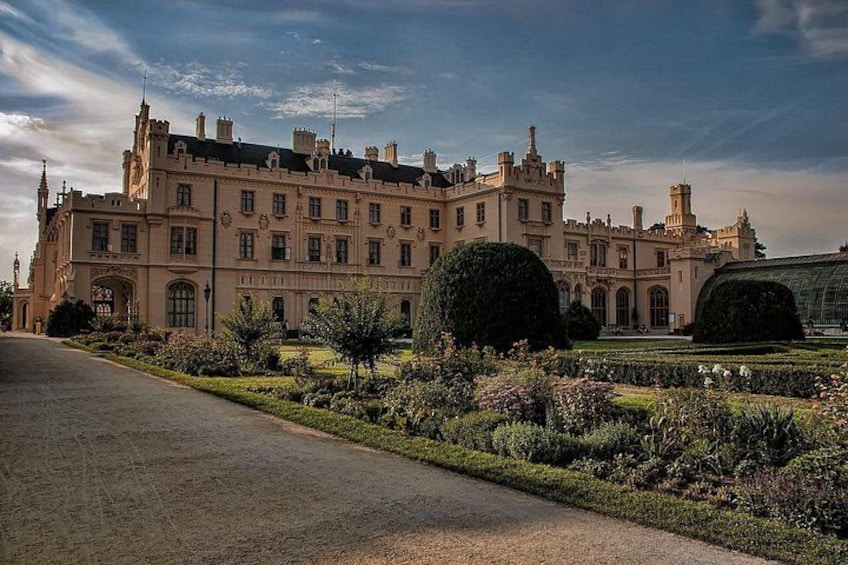A large, historic building with a formal garden in front. 1