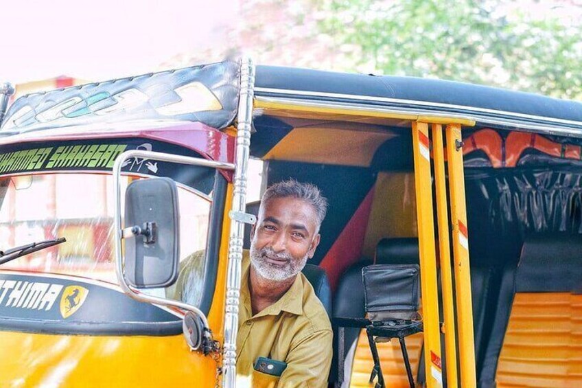 En mand sidder i en gul tuk-tuk med et sort tag. 4