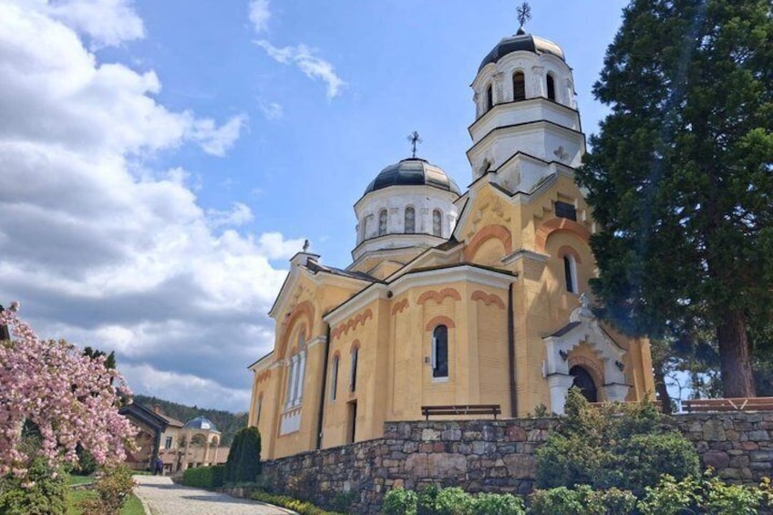 A church with multiple domes and a stone wall in front. 5