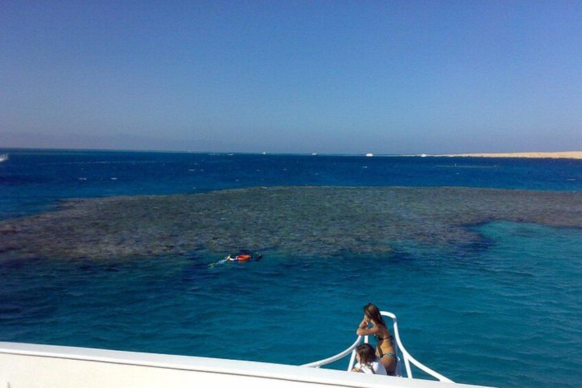 A boat on a clear blue sea with a sandy beach in the distance. 2