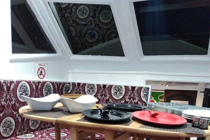 A dining table with plates and bowls, a patterned wall, and a window with a decorative ceiling. 3