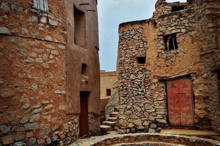A narrow alley with stone buildings, a wooden door, and a staircase. 3