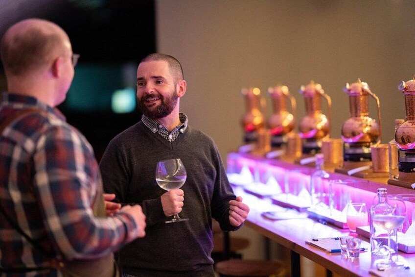 Two people conversing at a bar with wine glasses and copper decanters. 5