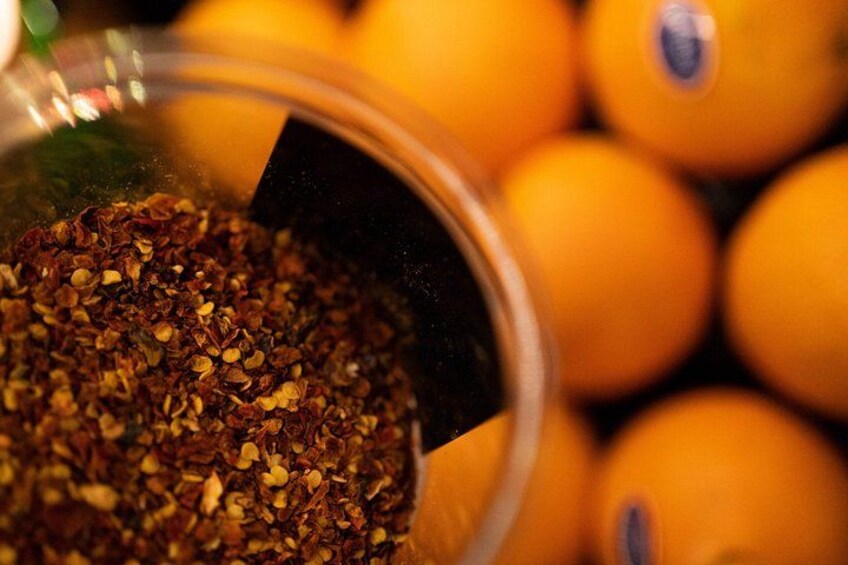 A close-up of a container with a mixture of spices and a background of oranges. 3