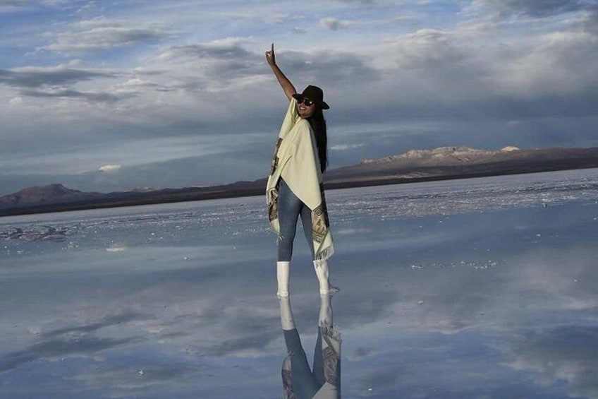 Una persona de pie sobre una superficie reflectante, con montañas al fondo. 4