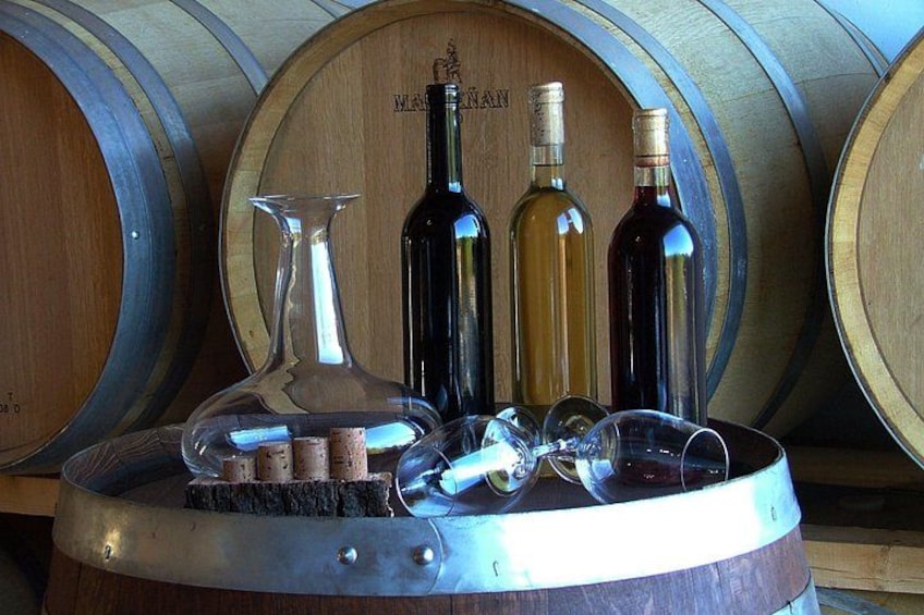 Wine bottles, a wine glass, and corks on a barrel. 3