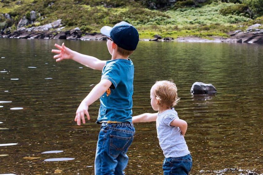 Two children standing by a lake with one pointing towards the water. 3