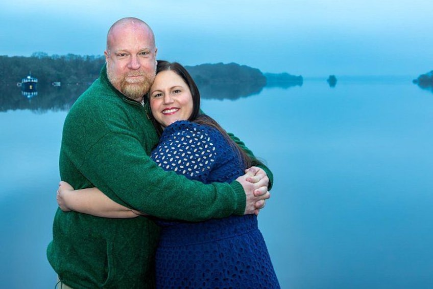 A couple embracing by a calm lake with a misty background. 1