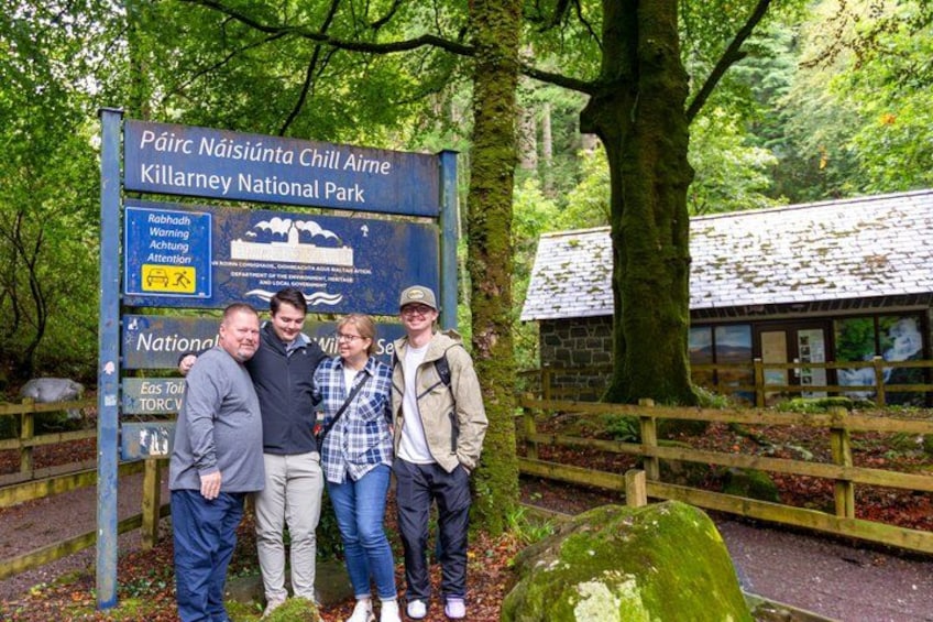 A group of people standing in front of a sign at Killarney National Park. 5
