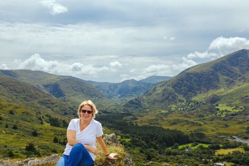 A person sitting on a rock with a mountainous landscape in the background. 3