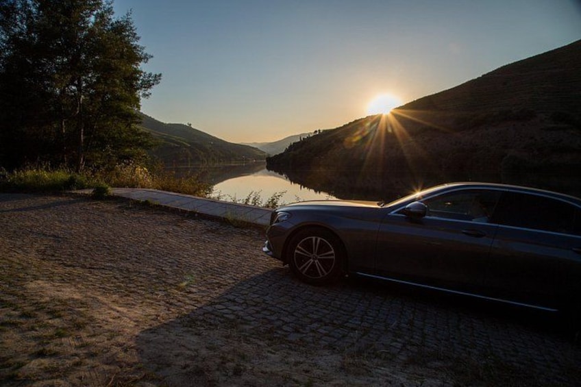 En bil parkeret ved en sø i solnedgang, med en sti ned til vandet. 4