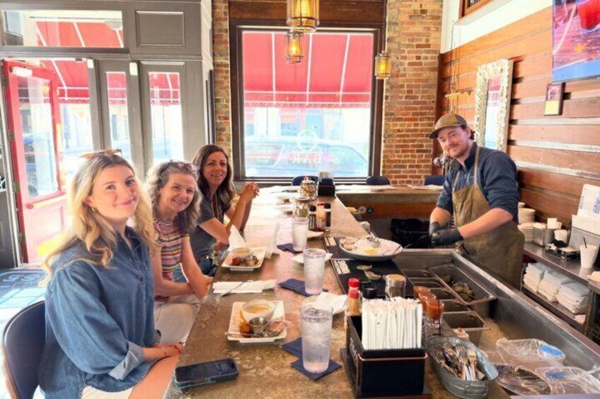 A group of people dining at a restaurant with a brick wall and large windows in the background. 3