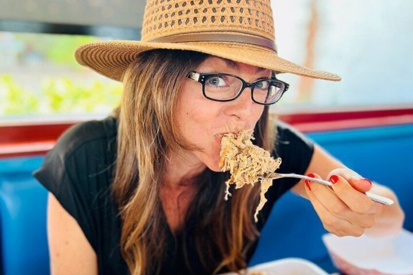 Una persona con sombrero de paja y remera negra, sosteniendo un tenedor con comida. 3