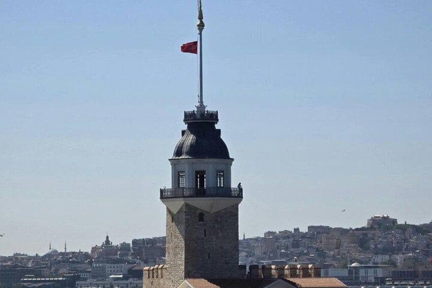 A tower with a flag, a clear sky, and a cityscape in the background. 2
