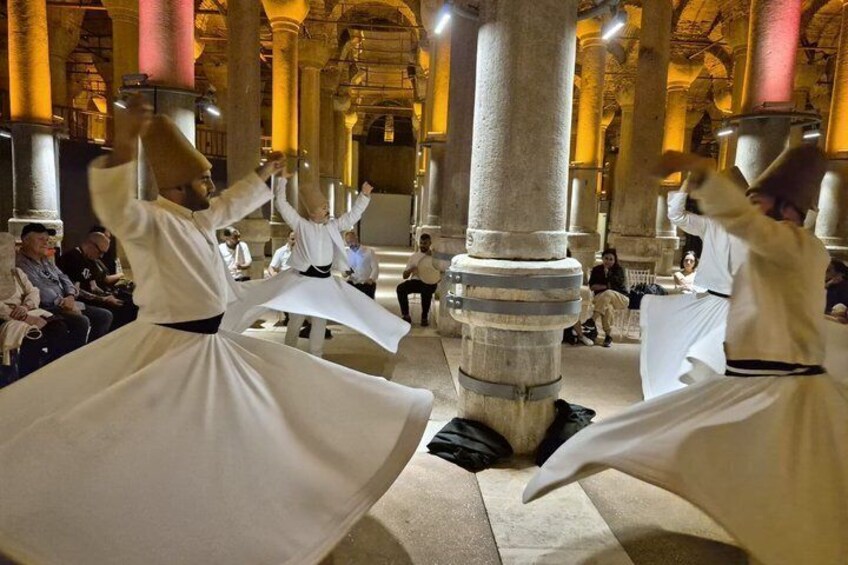 A group performing a traditional dance in a historic building with columns. 1