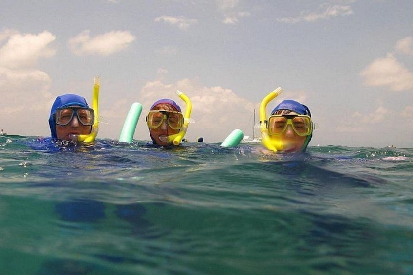 Three people snorkeling in the ocean with snorkels and masks. 4