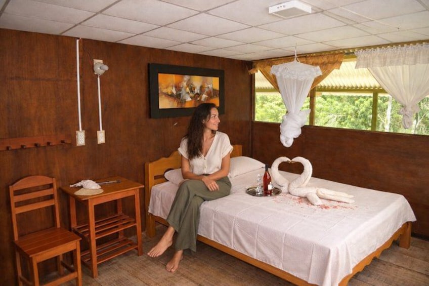 A room with a bed, a wooden chair, a small table, and a hanging mosquito net. 2