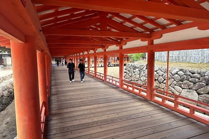A wooden walkway with red pillars, leading to a stone wall. 5